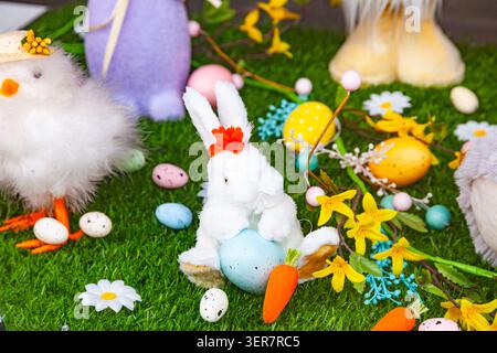 Easter background with plush bunny white chicken toy carrots and colorful painted eggs on green grass Stock Photo
