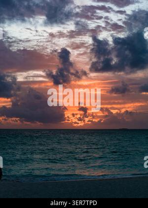 Sunset over calm ocean with cumulus clouds and Maldives islet Stock Photo