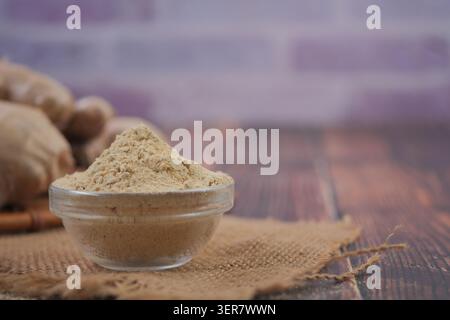 Ginger powder on a wooden table with fresh ginger nearby Stock Photo