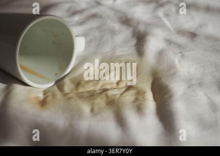 Cup spills coffee on a white tablecloth Stock Photo