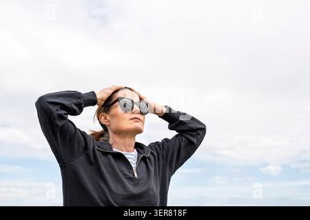 Thoughtful woman in sunglasses looking up towards the sky Stock Photo