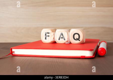 Wooden cubes with FAQ text on a red notebook Stock Photo