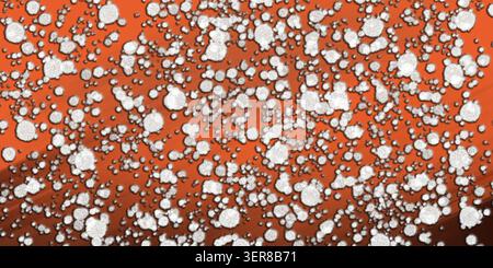 Abstract digital art background featuring a dense pattern of white, textured, circular particles scattered over a vibrant orange gradient surface. Stock Photo