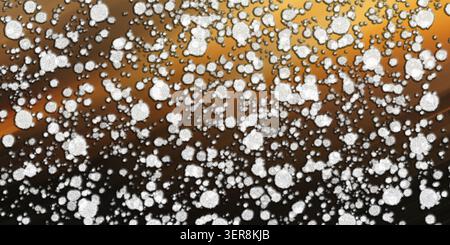 A vibrant abstract composition showing scattered white textured circles against a smooth, glowing golden-orange to dark brown diagonal gradient backgr Stock Photo