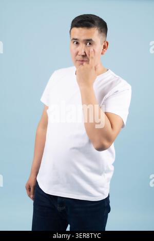 Thoughtful young man touching his chin looking away thinking deeply Stock Photo