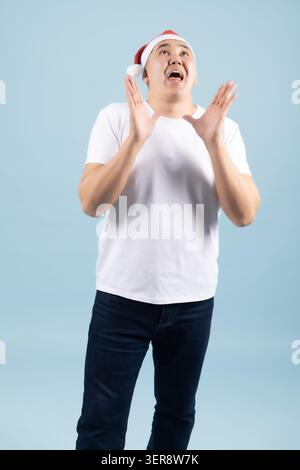 Amazed young man wearing santa hat looking up with open mouth Stock Photo