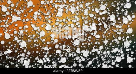 An abstract digital art composition featuring numerous white, textured, irregular circular particles scattered over a golden-green gradient background Stock Photo