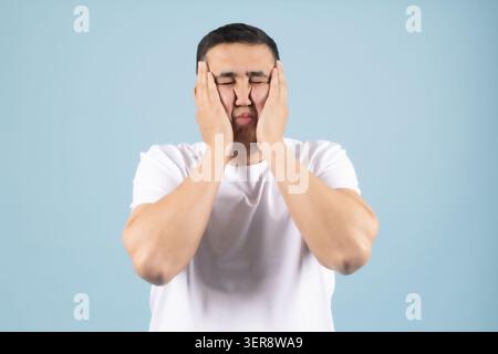 Exhausted young handsome man holding his head suffering from severe headache Stock Photo