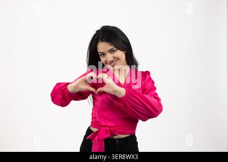 Happy young woman making cute heart shape with her hands and smiling bright Stock Photo