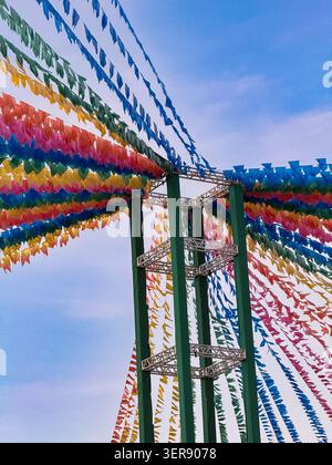 Brightly colored pennant flags strung across open space against blue sky. Decorations signal celebration, festival, or party event. Festive atmosphere Stock Photo