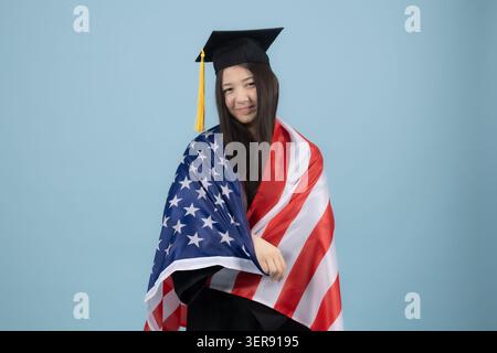 Graduate holding an American flag Stock Photo