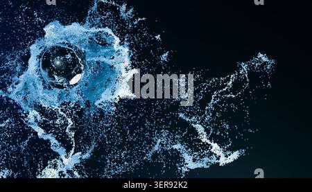 Abstract 3D render of a glossy blue sphere surrounded by a dynamic burst of tiny particles and fluid splash trails on a dark background, creating a fu Stock Photo