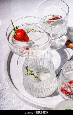 Elegant summer champagne cocktail in crystal glasses on a silver tray, garnished with fresh strawberry, chilli pepper and thyme, shot in bright natura Stock Photo