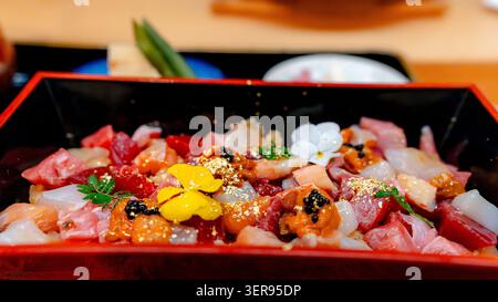 Colorful chirashi sushi bowl in a Tokyo Japanese restaurant, topped with Miyagi Pacific bluefin tuna, assorted seafood sashimi, roe, edible flowers, a Stock Photo