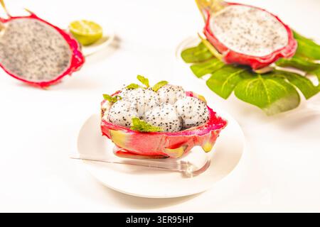 Close-up of ripe dragon fruit sliced open, revealing its vibrant white interior shaped into small fruit balls containing tiny black seeds. The fruit i Stock Photo