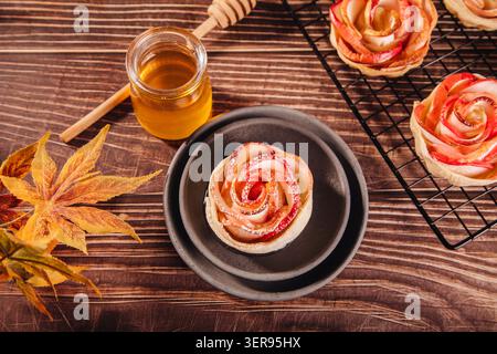 A beautiful rose-shaped apple dessert sits elegantly on a black plate. This baked sweet treat features intricately sliced apples designed to resemble Stock Photo