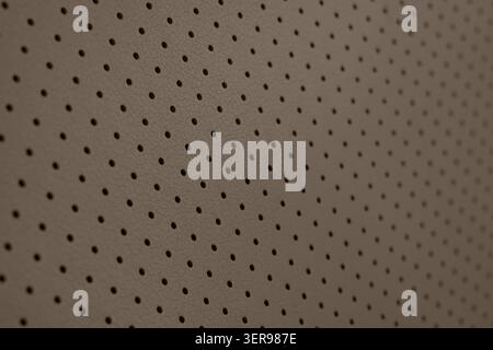 Close-up of a brown textured surface featuring evenly spaced small perforations, providing a unique pattern ideal for backgrounds, backdrops, or desig Stock Photo