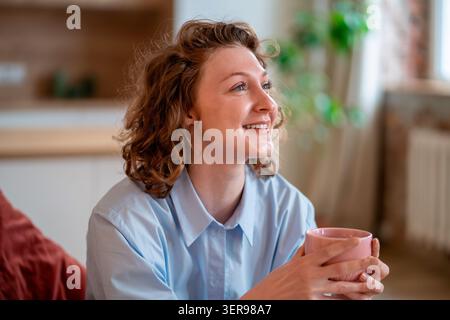 Smiling happy woman enjoying coffee break feeling mental wellbeing, gratitude, balanced lifestyle. Stock Photo