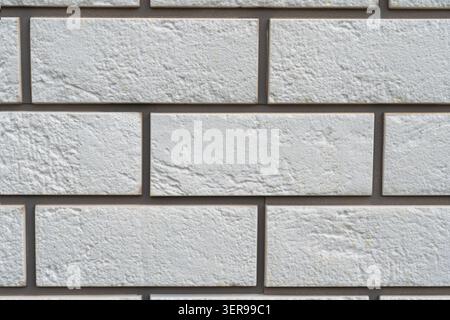 Close-up of a white brick wall showcasing a textured, rough surface. The uniform pattern of the bricks creates a natural yet structured background, id Stock Photo
