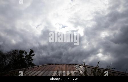 Dark dramatic storm clouds gathering over rooftop before heavy rain begins Stock Photo