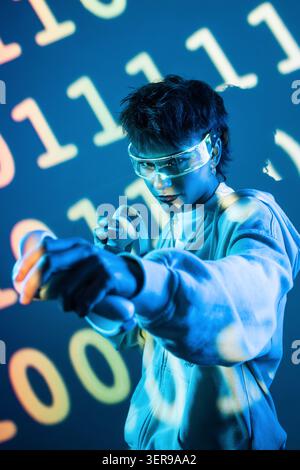 Futuristic cyberpunk young woman wearing virtual reality goggles, pointing toward the viewer in blue neon light with binary code projection, exploring Stock Photo