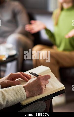 Female Therapist Taking Notes during Adult Couples Counseling Stock Photo