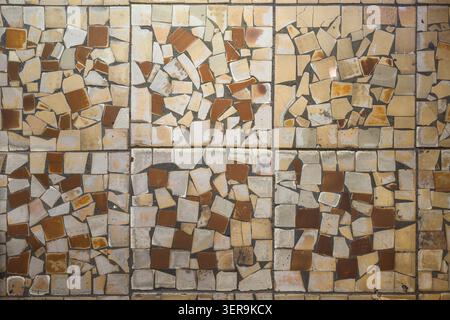Detailed overhead view of a mosaic made from broken ceramic tiles. Earthy tones of cream, beige, and brown create a textured, abstract pattern. Stock Photo