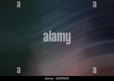 An abstract dark background featuring subtle diagonal streaks of light and soft color transitions with a prominent grainy texture. Stock Photo