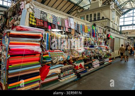 Selection of colourful bolts of fabric on sale at a market stall selling sewing and needlework goods in Cardiff market, South Wales, UK Stock Photo