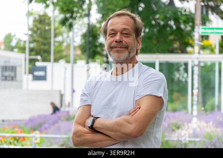 Man about 55 years old standing with crossed arms in an urban environment Stock Photo
