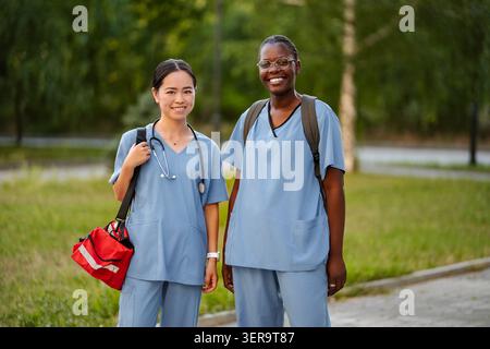Diverse female healthcare students smiling outdoors, ready for their medical studies Stock Photo
