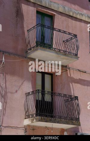 Pink building with ornate wrought iron balconies in the historic village of Palizzi, Aspromonte National Park, Calabria Southern Italy. Stock Photo