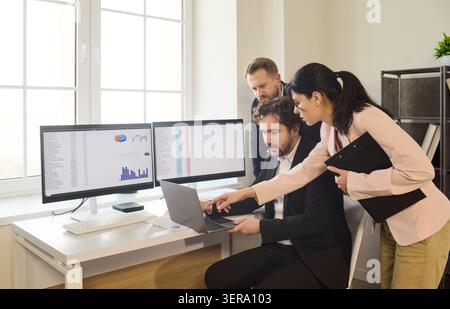 Colleagues collaborating on analytics at workstations, business data review Stock Photo