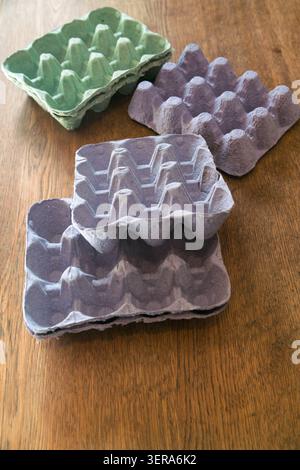 Empty egg cartons made of molded paper pulp, in pastel colors, on a wooden table Stock Photo