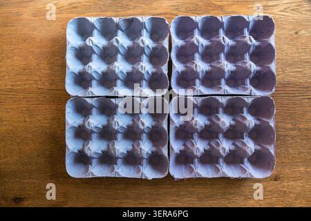 Four empty purple cardboard egg cartons creating a visual grid on a wooden background Stock Photo