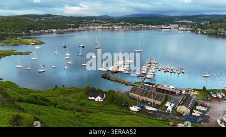 A peaceful aerial view over Oban Bay, where sailboats rest on calm waters beneath the dramatic skies of Scotland's west coast Stock Photo