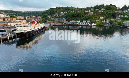 A peaceful aerial view over Oban Bay, where sailboats rest on calm waters beneath the dramatic skies of Scotland's west coast Stock Photo