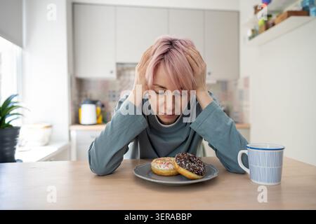 Depressed stressed mature woman suffering from psychological issues and overeating sweet food, Stock Photo