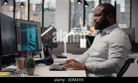 Black worker creating fantasy video game with AI neural networks systems, using advanced development software. Engineer working with programming tools and gaming assets, building virtual world. Stock Photo