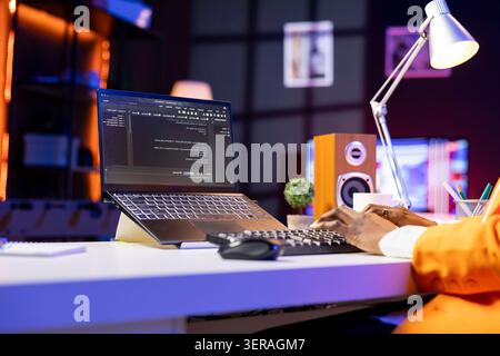 Engineer at desk typing code on notebook device, developing software programs, entering commands. Person at home fixing errors in application, implementing new features, close-up. Stock Photo
