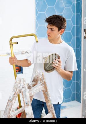 Focused guy assembling shower set before fixing to wall Stock Photo