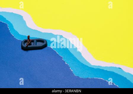 Miniature Person Seated In Small Dinghy Boat Floating On Blue Wavy Water Against Yellow Sky Backdrop Stock Photo