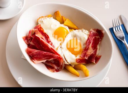 Fried eggs with french fries and slices of jamon Stock Photo