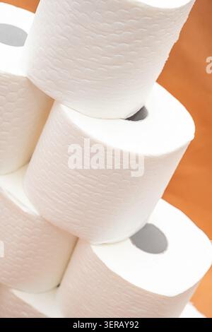 Rolls of white paper towels stacked in a kitchen pantry with a wooden shelf and warm lighting during day. kitchen pantry, several rolls of white paper towels are stacked neatly on a wooden shelf. Stock Photo