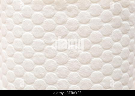 Close up view of textured surface with pattern of small circles. surface shows design of small circles arranged in a grid. circles are even create uniform look. colors l soft, surface appear smooth Stock Photo