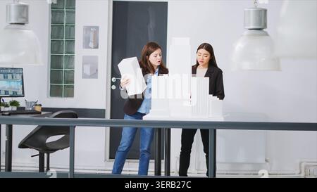 Specialists examine 3D models to decide on measurements while developing small business growth ideas, team of architects construct floor plan strategy with industrial scale dimensions. Stock Photo