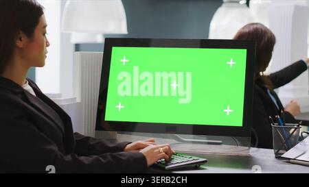 CAD designer using PC with green screen at workstation area, examining monitor with blank copyspace design in startup company, engineer uses isolated chromakey display on computer. Stock Photo