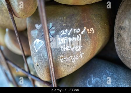 Hand-painted river stone reading "Eat the Rich" stacked inside a wire mesh wall, Christchurch, New Zealand. Stock Photo