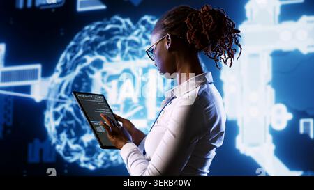 IT specialist updating AI systems, writing intricate binary code scripts on tablet, visualizing result wth AR, Licensed employee using programming to upgrade artificial intelligence simulation model. Stock Photo