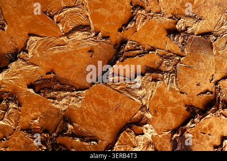 Abstract golden texture background of crumbled gold leaf and metallic foil pieces with deep shadows and reflections Stock Photo